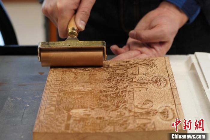 圖為徐晉林工作室工作人員正在給雕好壁畫的版面滾油墨。　九美旦增 　攝