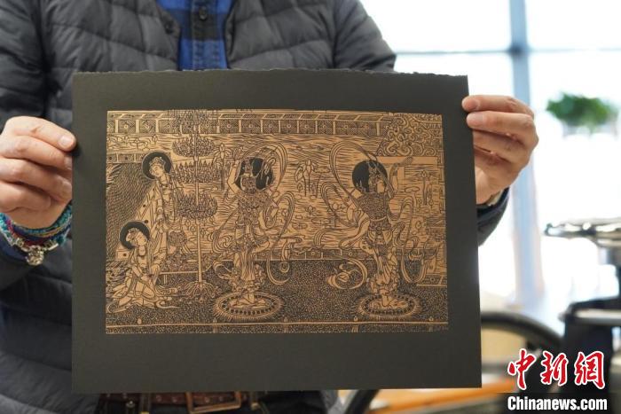 圖為手工書藝人展示敦煌雕版壁畫印刷品。　九美旦增 　攝