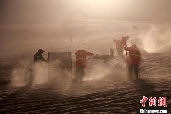 圖為敦煌市鳴沙山月牙泉景區(qū)“駱駝保姆”清理駱駝糞便?！垥粤?攝