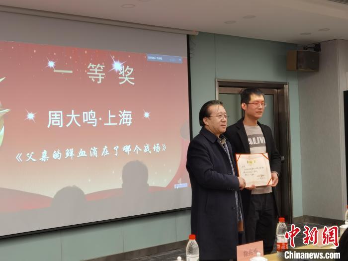 圖為作家、西北師范大學(xué)新聞與傳媒學(xué)院院長(zhǎng)徐兆壽頒發(fā)一等獎(jiǎng)證書(shū)，代領(lǐng)獎(jiǎng)?wù)呱吓_(tái)領(lǐng)獎(jiǎng)?！钅?攝