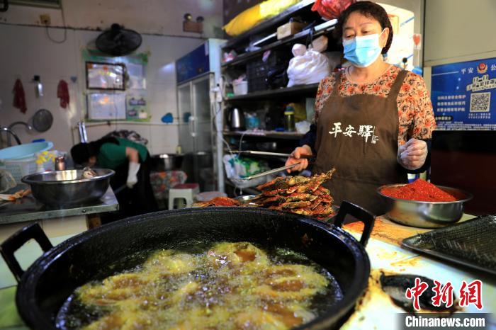 圖為平安驛·河湟民俗文化體驗(yàn)地內(nèi)的商戶炸干板魚?！⊙Φ?攝
