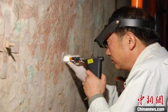 敦煌研究院研究員樊再軒進(jìn)行壁畫修復(fù)。(資料圖)張?jiān)莆?攝