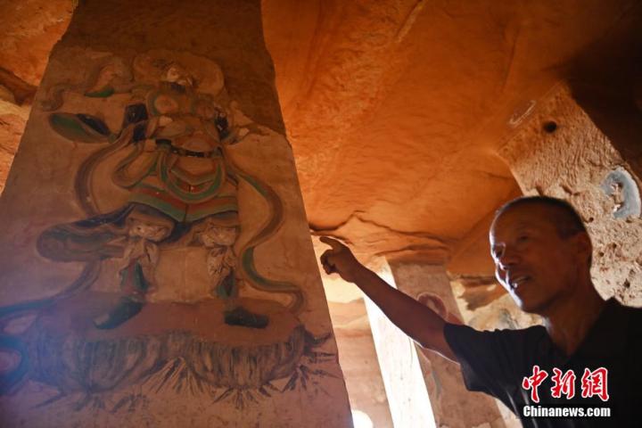 7月15日，甘肅省平?jīng)鍪袥艽h百里石窟長(zhǎng)廊羅漢洞石窟內(nèi)，該窟文保員郭建平介紹窟內(nèi)石刻彩繪壁畫(huà)。郭建平家中三代人曾自發(fā)保護(hù)羅漢洞石窟。羅漢洞石窟遺存40余個(gè)窟龕，以北魏至清代風(fēng)格為主。中新社記者 李亞龍 攝</p>
<p>